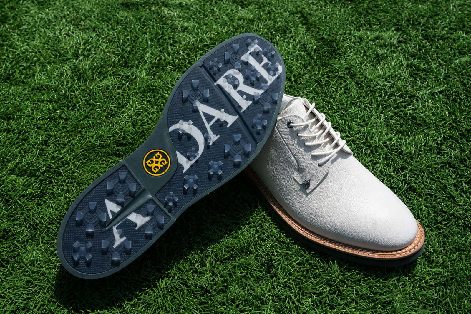 White G/FORE x Adare Manor golf shoe on grass with navy ADARE-branded sole