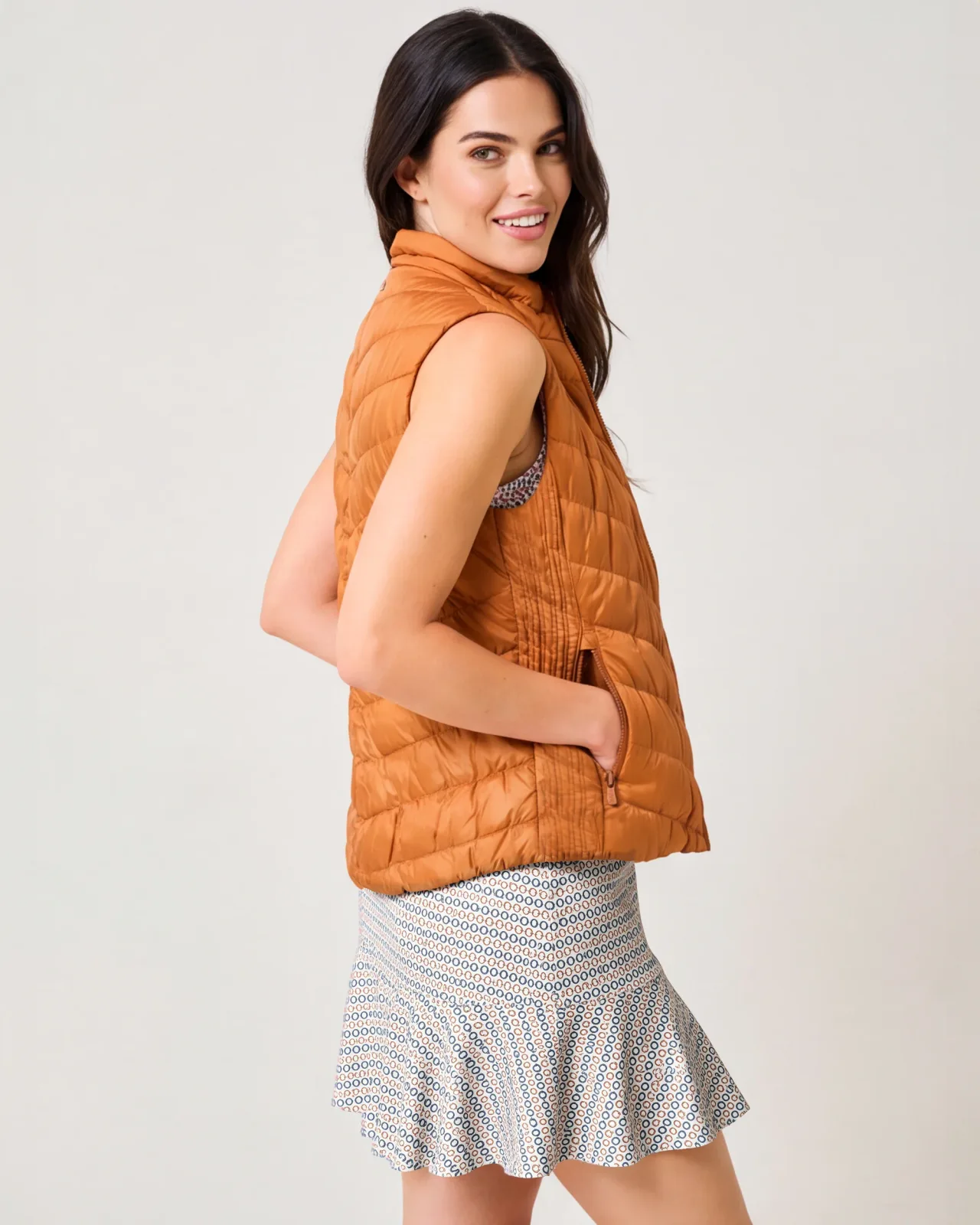 Woman in a copper quilted vest over a geo-print skort